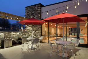 two tables and chairs with red umbrellas on a patio at Home2 Suites By Hilton Leavenworth Downtown in Leavenworth