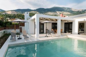 a house with a swimming pool with chairs and umbrellas at Villa Petra in Trapezaki