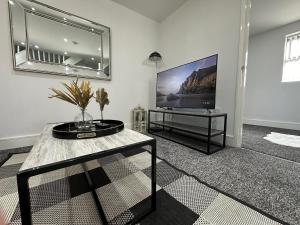 a living room with a flat screen tv on a wall at THE GLASS HOUGHTON APARTMENTS in Castleford