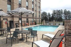 a pool with tables and chairs and an umbrella at Hampton Inn Forsyth in Forsyth