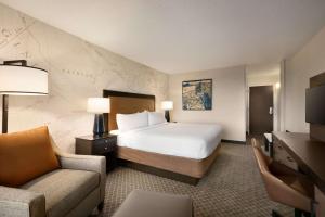 a hotel room with a bed and a couch and a chair at DoubleTree by Hilton McLean Tysons in Tysons Corner
