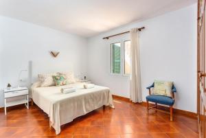 um quarto com uma cama, uma cadeira e uma janela em Villa Miguels em Es Mercadal