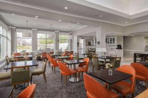 a restaurant with tables and chairs and windows at Hilton Garden Inn Overland Park in Overland Park