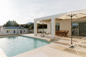 a house with a swimming pool with chairs and an umbrella at Villa Kira in Trapezaki