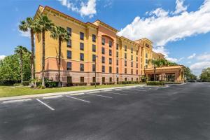 ein großes gelbes Gebäude mit Palmen vor einer Straße in der Unterkunft Hampton Inn & Suites Orlando-South Lake Buena Vista in Kissimmee