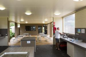 un hombre parado en un mostrador en una cocina en NRMA Eastern Beach Holiday Park, en Lakes Entrance