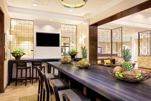 Hampton Inn & Suites Orlando/Downtown South - Medical Center في أورلاندو: غرفة طعام مع طاولة طويلة مع كراسي وتلفزيون