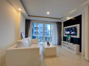 Una sala de estar con un sofá blanco y un televisor. en Grand Avenue Residence condominium, en Pattaya central