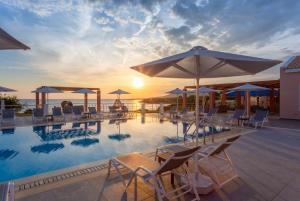 a swimming pool with chairs and umbrellas and the ocean at Nafsika Beach House in Dhamoulianáta