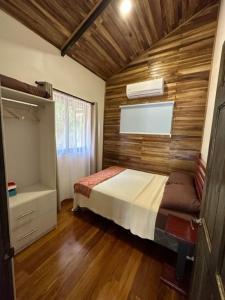 1 dormitorio con 1 cama y pared de madera en Casa Cooper en Carrillo