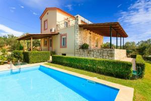 a villa with a swimming pool in front of a house at Kalyves Villas Collection in Áyios Andónios
