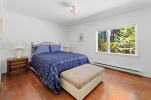 a white bedroom with a bed and a window at Seaside Country Cottage in Saanichton