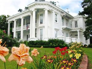 a white house with flowers in front of it at Hilton Garden Inn Meridian in Meridian