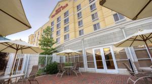 a hotel with tables and chairs and umbrellas at Hilton Garden Inn Meridian in Meridian