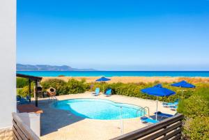 a swimming pool with blue umbrellas and the beach at Blue Bay Villa Nicole in Mavroli