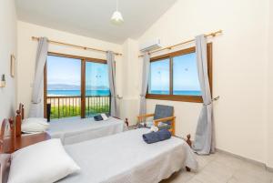 a bedroom with two beds and a view of the ocean at Blue Bay Villa Nicole in Mavroli +32 photos