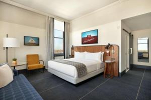 a hotel room with a bed and a chair at The Central Station Memphis, Curio Collection By Hilton in Memphis