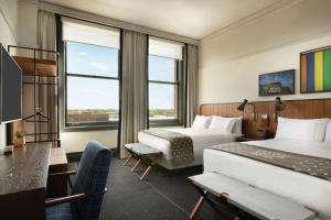 a hotel room with two beds and a desk at The Central Station Memphis, Curio Collection By Hilton in Memphis