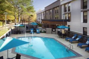 a swimming pool with chairs and umbrellas next to a building at Hampton Inn Memphis/Collierville in Collierville