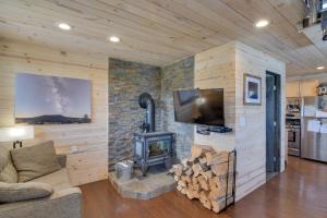 a living room with a fireplace with a tv and a stove at Secluded Jefferson Cabin with Deck and Mountain Views! in Bordenville