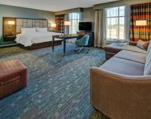 a hotel room with a bed and a couch and a table at Hampton Inn & Suites Memphis Germantown in Memphis