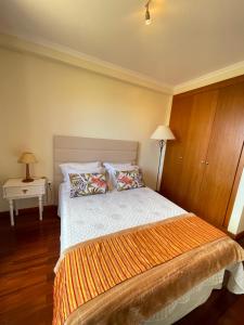 een slaapkamer met een groot bed en een oranje deken bij Cantinho da Té in Câmara de Lobos