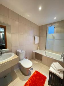 a bathroom with a toilet and a tub and a sink at Cantinho da Té in Câmara de Lobos