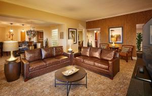 a living room with brown leather couches and a table at Doubletree by Hilton Phoenix Mesa in Mesa