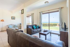 ein Wohnzimmer mit einem Ledersofa und einem TV in der Unterkunft Blue Bay Villa Thea in Mavroli