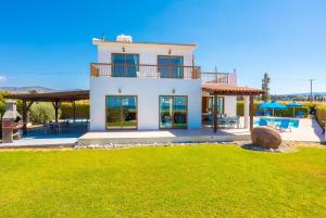 een groot wit huis met een patio en een tuin bij Blue Bay Villa Thea in Mavroli