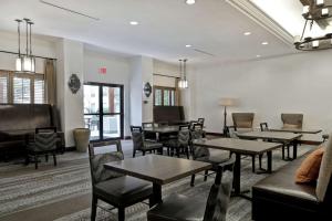 una sala d'attesa con tavoli e sedie in un edificio di Homewood Suites by Hilton McAllen a McAllen