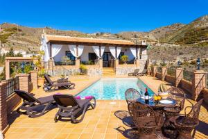 a pool with chairs and a table and a house at Villa Flores in Almuñécar