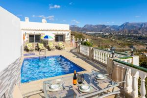 a villa with a swimming pool and a table with a bottle of wine at Villa Alegria in Torrox