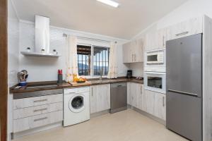 a kitchen with white cabinets and a washer and dryer at Villa Alegria in Torrox
