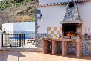 a fireplace on a patio next to a pool at Villa Alegria in Torrox