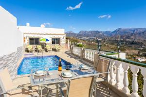 a villa with a swimming pool and a balcony with a table at Villa Alegria in Torrox