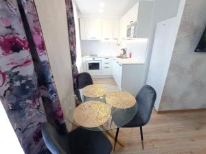 eine kleine Küche mit einem Glastisch und Stühlen in der Unterkunft New Energia apartment in center city in Narva
