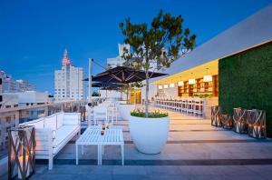 a row of white tables and benches on a rooftop at Gale South Beach, Curio Collection By Hilton in Miami Beach