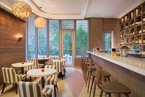 a restaurant with tables and chairs and windows at Gale South Beach, Curio Collection By Hilton in Miami Beach