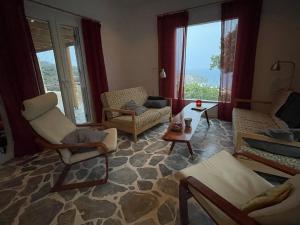 uma sala de estar com cadeiras, uma mesa e janelas em VillaNova em Drymonas