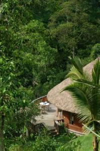 a house with a thatched roof with a porch and a table at Bagus Jati Health & Wellbeing Retreat in Tegalalang