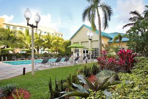 a resort with a swimming pool and palm trees at Homewood Suites by Hilton Miami - Airport West in Miami