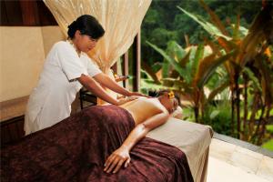 a woman getting a massage from a woman sitting on a bed at Bagus Jati Health & Wellbeing Retreat in Tegalalang