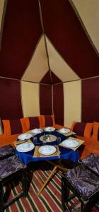 einen Tisch in einem Zelt mit Tellern darauf in der Unterkunft Zagora Desert Camp in Bou Khellal