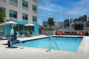 a swimming pool with chairs and tables and a building at Tru By Hilton Miami West Brickell in Miami