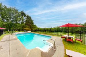 a swimming pool with a table and an umbrella at Holden Frost House in Franconia