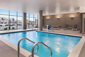 a pool in a hotel with chairs and a table at Hilton Garden Inn Milwaukee Brookfield Conference Center in Brookfield