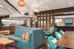 a waiting room with a blue couch and tables at Tru By Hilton Milwaukee Brookfield in Waukesha