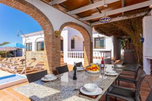 een patio met een tafel en stoelen en een zwembad bij Villa Alta Vista in Frigiliana