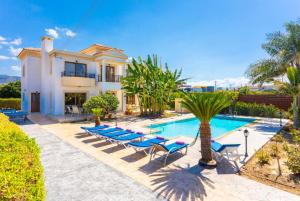 a villa with a swimming pool and palm trees at Villa Dora in Argaka